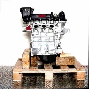 Side view of the 1KR-FE engine on a wooden pallet against a white background. The silver engine with black components is vertically oriented.