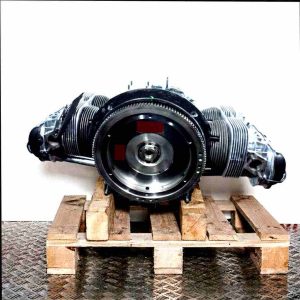 Side view of an AJ engine on a wooden pallet against a white background. The engine is horizontally aligned, showcasing all its components.