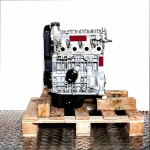 Side view of a grey APQ engine on a wooden pallet against a white background. The engine features black components and shiny metal parts.
