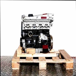 Side view of an APX engine in silver and black on a wooden pallet. The engine is set against a white background and features an oil filter.