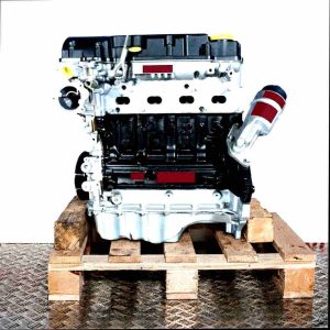 Side view of a B 14 XER engine on a wooden pallet. The engine block is black, the cylinder head silver with yellow accents. The white background provides a clean backdrop.