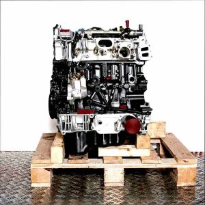 Side view of a BKRA engine on a wooden pallet against a white background. The black and silver engine block displays intake ports, connectors, and the oil pan. The engine is vertically oriented.