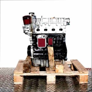 Side view of a BWK engine on a wooden pallet against a white background. The silver top and black bottom of the engine are visible, along with the oil filter. The oil pan is silver.