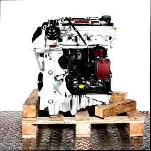 Side view of a CMGB car engine on a wooden pallet against a white background. The engine, in black, silver, and yellow, is positioned vertically.