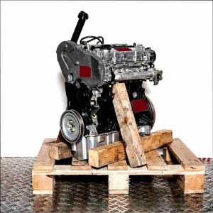 DAUA engine on a wooden pallet against a white background. Side view of the black engine with silver accents, vertically oriented. Detailed shot.