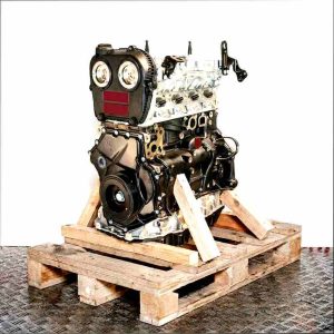 Black DKTB car engine on a wooden pallet against a white background. The engine with a silver cylinder head is fully visible from the side.