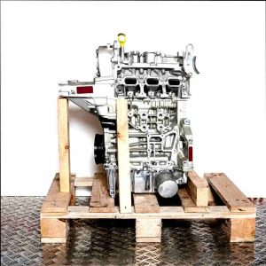 Side view of a silver engine with black and yellow accents, model DLAA, on a wooden pallet against a white background. The engine is vertically oriented.