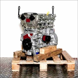 F 12 SHT engine on a wooden pallet against a white background. Side view showcasing engine components like camshafts and timing belt.