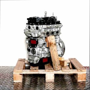 Side view of an F 12 XHT (EB2ADTS) engine on a wooden pallet against a white background. The silver engine with black parts is fully visible.