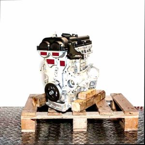 G4FD engine on a wooden pallet against a white background. Side view of the internal combustion engine, vertically oriented.