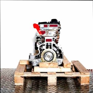 H9FD engine on a wooden pallet against a white background. The engine, made of metal and plastic, is vertically oriented.